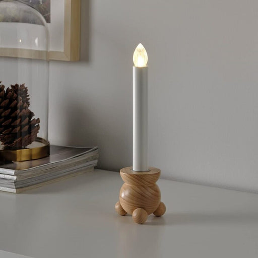 Battery-operated LED candle holder by IKEA, the STRALA model, emitting a warm glow in a cozy home setting.