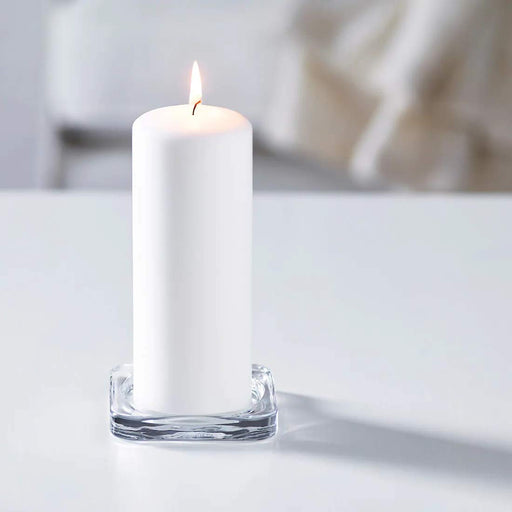 A white candle with a round base is placed in the candle dish