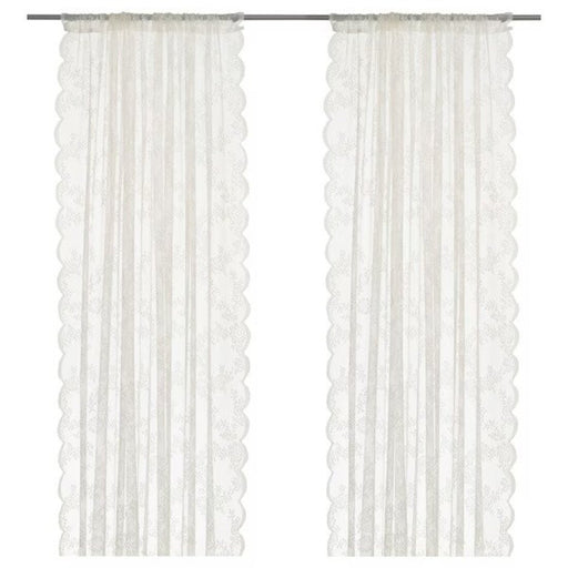 A pair of white curtains with floral patterns drawn to the side, revealing a bright and sunny room.40171863