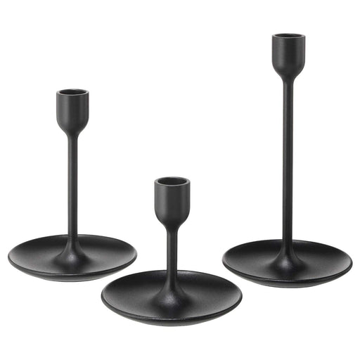The set of three IKEA candlesticks arranged on a mantle, with candles in each one.