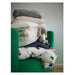 Stack of folded clothes and a plush toy on a green chair against a neutral background