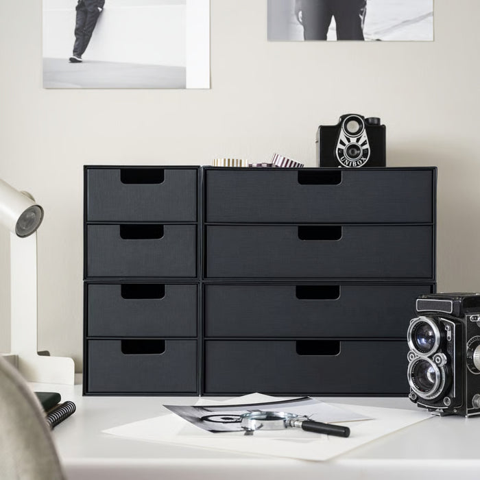 Black storage drawers on a desk with office supplies in a minimalistic office setting