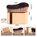 gold curved makeup brush with soft fiber wool bristles standing upright on flat bottom surface
