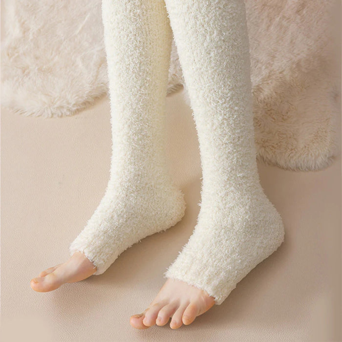 Legs in thick milky white fuzzy leg warmers extending from feet to thighs on soft rug - 