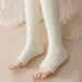 Legs in thick milky white fuzzy leg warmers extending from feet to thighs on soft rug - 