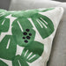 Green leaf patterned pillow on a gray couch