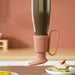 Pink boot-shaped cup holder on a pink background with a dessert in the foreground