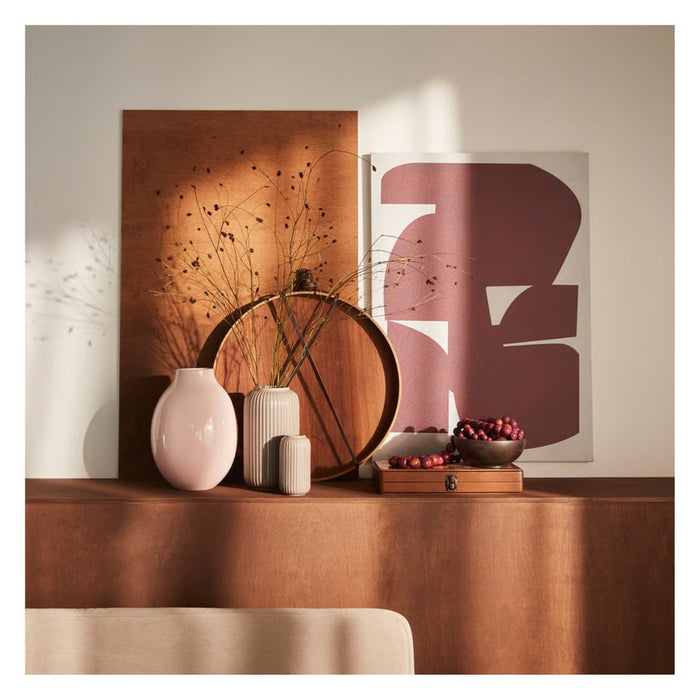 Decorative setup with vases, a bowl, and abstract art on a table.