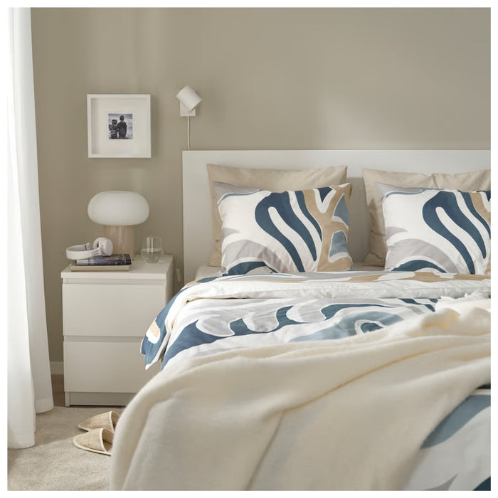 Neatly made bed with patterned bedding in a bedroom setting.