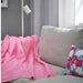 DAGGKÅPOR throw, pink, 130x170 cm. Draped over light grey sofa with abstract cushion, white floor lamp, and grey curtains – adds soft, cosy charm to living room – 00598645.