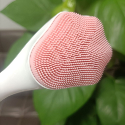 Hand holding a pink silicone facial brush for pore cleansing