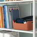 Bookshelf with books and a brown basket on a white shelf