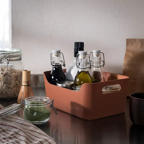 Ceramic tray with various kitchen items including bottles and jars on a wooden surface.