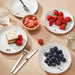  IKEA SPJUTLILJA patterned plates styled with assorted fruits and cake on a dining table
