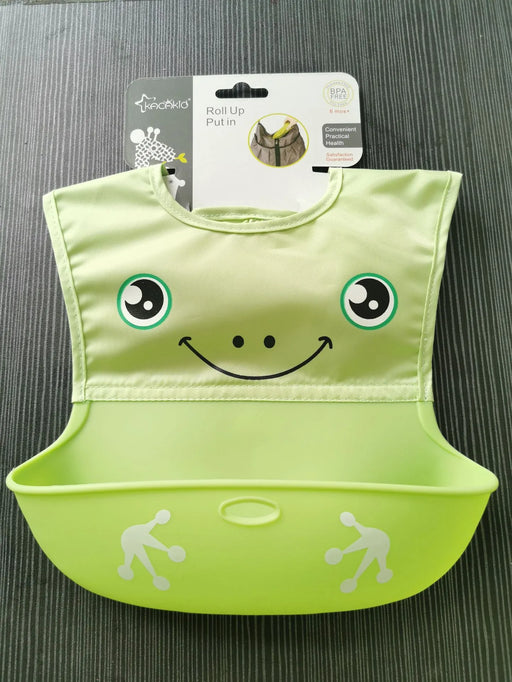 Green baby bib with smiley face design on a gray surface
