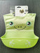 Green baby bib with smiley face design on a gray surface