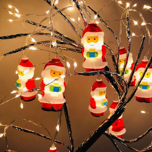 Decorative string lights shaped like Santa Claus figures on a branch with a warm background.