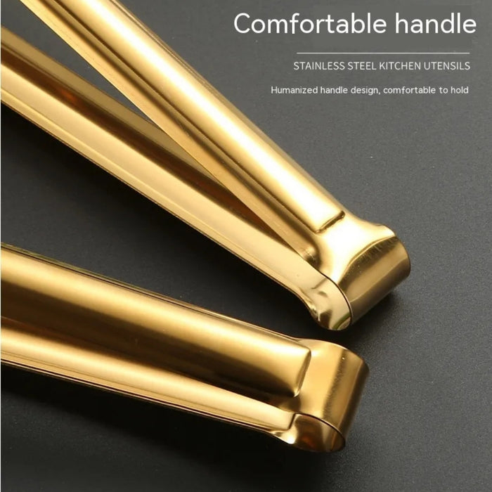 Close-up of two golden stainless steel kitchen tongs with a focus on their long, ergonomic handles. Text on the image reads: “Comfortable handle – STAINLESS STEEL KITCHEN UTENSILS – Humanized handle design, comfortable to hold.” The curved handles appear smooth and well-balanced, ideal for extended use during cooking or serving hot foods.- 1600003112384 13034149
