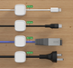 Six black magnetic cable clips arranged in packaging with under-desk mounting demonstration