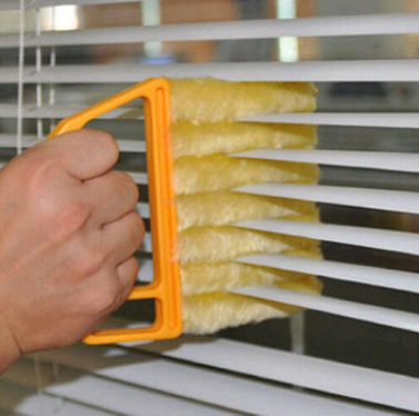 Cleaning brush removing dust from horizontal window blinds
