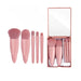 Set of pink makeup brushes with a mirror in a box on a white background