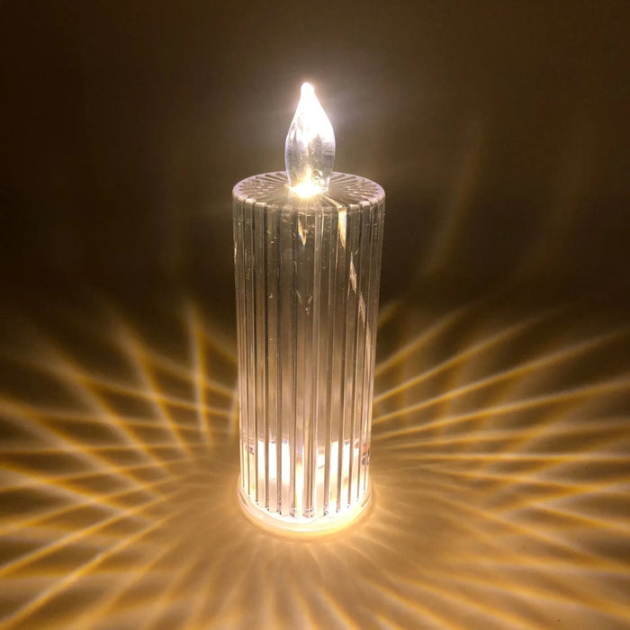 Decorative candle with a ribbed glass holder on a dark background