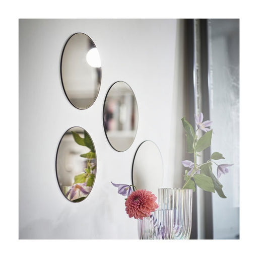 Decorative wall mirrors with floral reflections on a white wall.