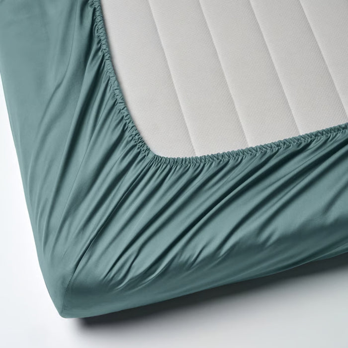 Teal fitted sheet on a mattress with a white background