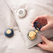 Small round devices with a hand interacting with one of them on a light fabric background
