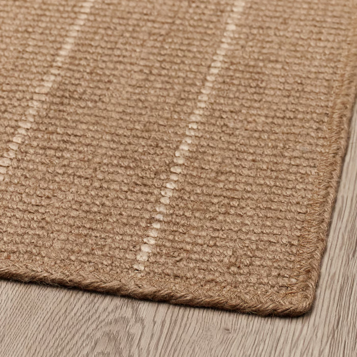 Close-up of a textured brown rug on a wooden floor