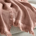 KLOTSTARR throw, pale pink, 130x170 cm – waffle-knit texture with fringed edges, draped over light sofa. Soft cotton blend dyed using beetroot residue – 50562031.