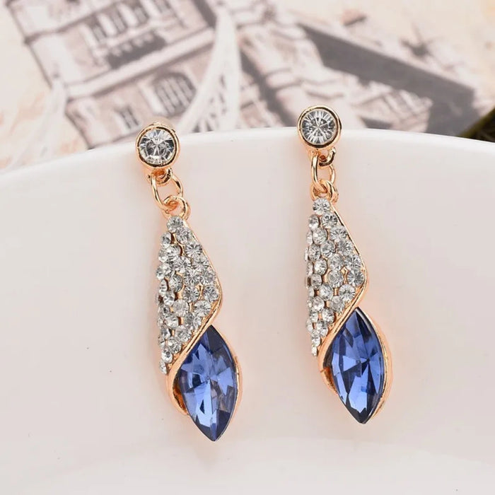 Pair of earrings with blue gemstones and rose gold accents on a white surface.