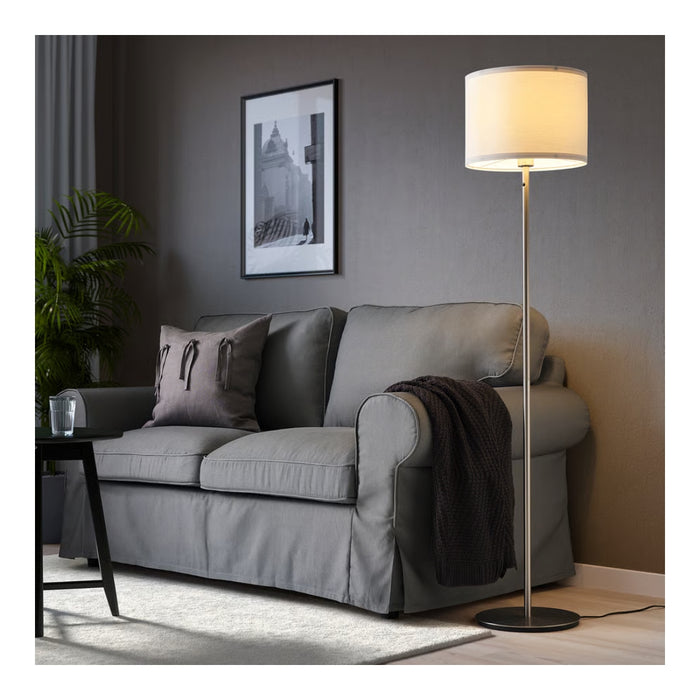 Gray sofa in a living room with a floor lamp and framed picture on the wall.