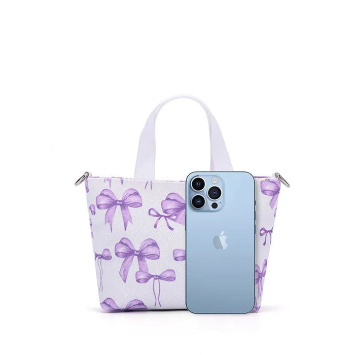 Canvas Shoulder Bag – Purple Bow Print, 15×6.5×13.5cm Fashion Tote, shown with iPhone for size comparison