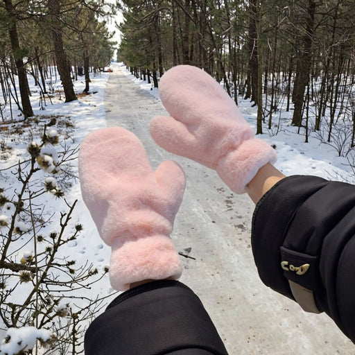 fluffy pink mittens worn outdoors in snowy forest path