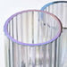Clear glass vase with a purple rim against a white background