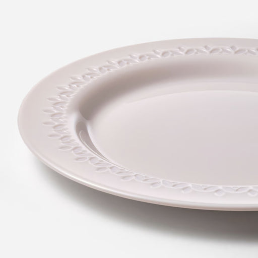 White ceramic plate with decorative edge on a light gray background