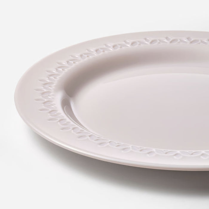 White ceramic plate with decorative edge on a light gray background