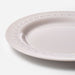 White ceramic plate with decorative edge on a light gray background