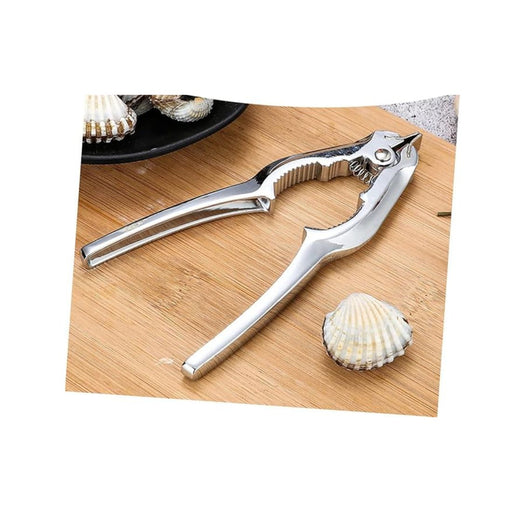 Metallic shell opener on a wooden surface with a shell nearby