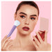 Woman holding a beauty tool and compact mirror against a pink background
