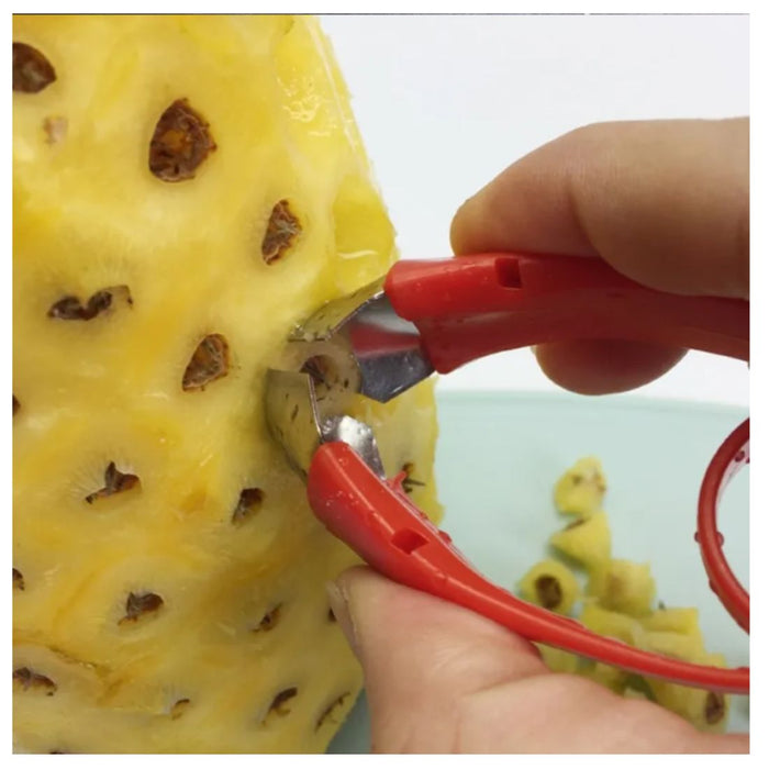Person using a red pineapple peeler to remove skin from a yellow pineapple.