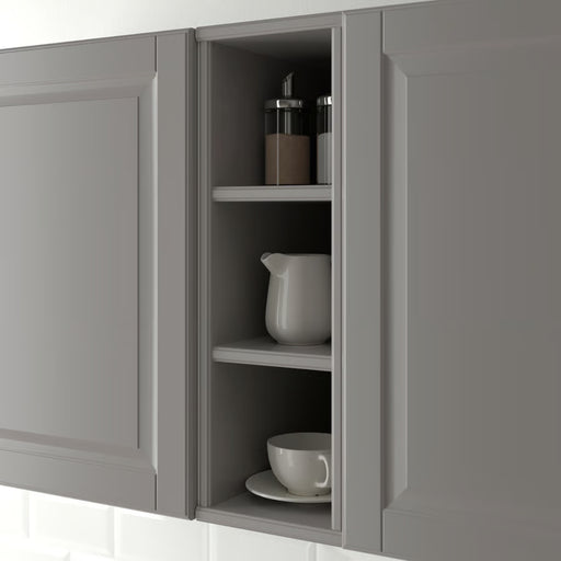 TORNVIKEN cabinet styled in a kitchen wall niche, holding ceramic pitcher, teacup, and spice jars against white tile backdrop