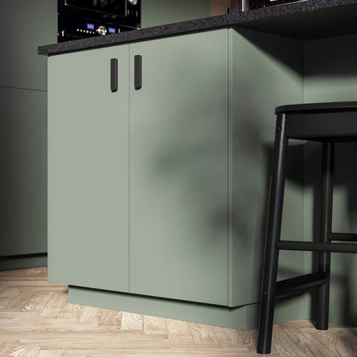 Green kitchen cabinet with a black bar stool in a modern kitchen setting