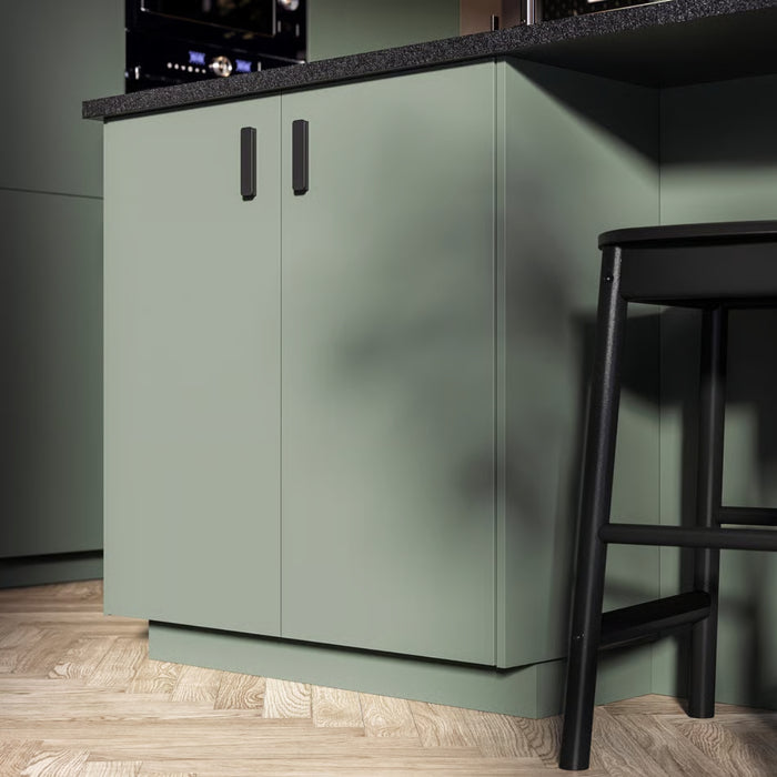 Green kitchen cabinet with a black bar stool in a modern kitchen setting