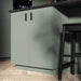 Green kitchen cabinet with a black bar stool in a modern kitchen setting