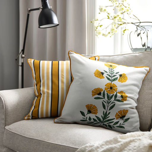 Decorative pillows on a sofa with a lamp and window in the background