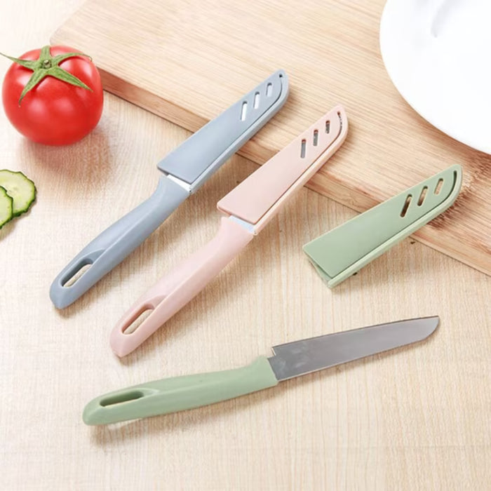 Three colorful kitchen knives on a wooden surface with vegetables.