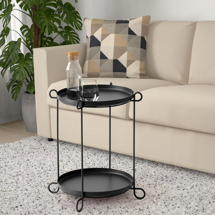 Black side table with a bottle and glass in a living room setting