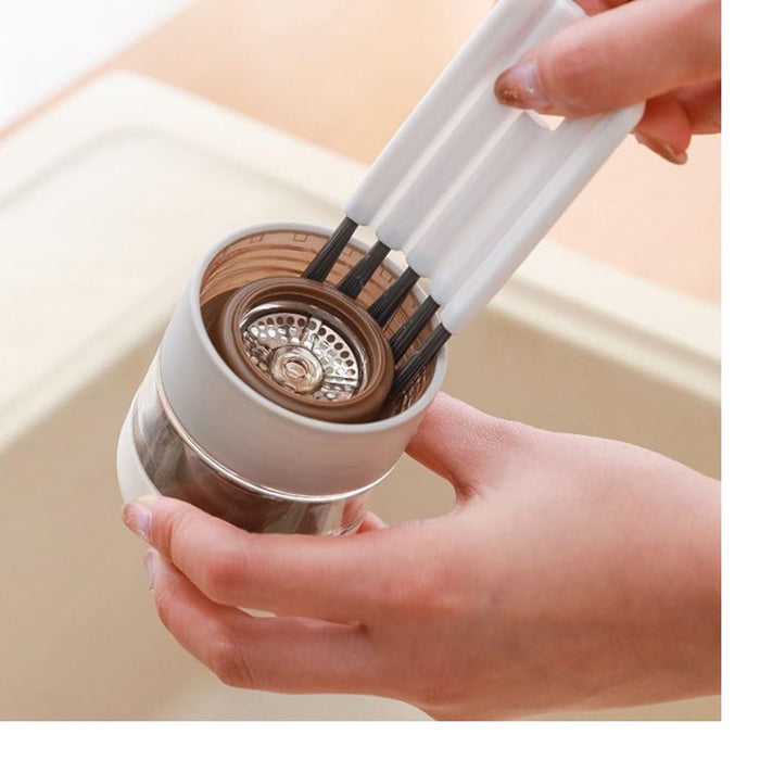 Person using a kitchen scrubber to clean a glass container with a strainer.